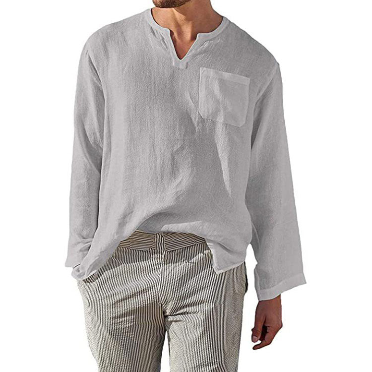 Camicia uomo bianca in lino, manica lunga, con taschino, scollo a V, abbinata a pantaloni a righe. Stile casual elegante, moda estiva.