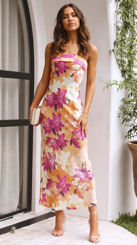 Abito lungo estivo a fiori rosa e arancioni, senza spalline, indossato da una donna. Perfetto per eventi eleganti e cerimonie all'aperto.