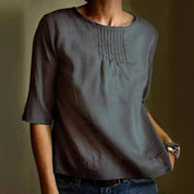 Blusa donna grigia a maniche tre quarti, con dettagli plissettati sul petto. Moda casual elegante, ideale per abbigliamento quotidiano.