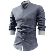 Camicia uomo in denim blu, maniche lunghe, colletto button-down, taschino frontale, bottoni bianchi. Elegante e casual, moda maschile.