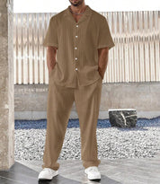 Uomo in completo estivo marrone a righe, camicia a maniche corte e pantaloni abbinati, indossa scarpe bianche. Moda casual maschile elegante.