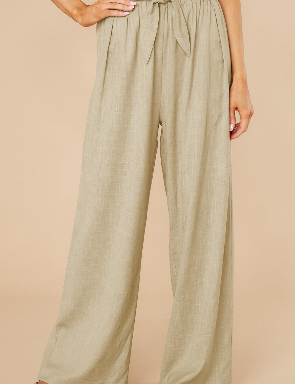 Pantaloni a vita alta beige da donna, con cintura annodata, design ampio e tessuto leggero. Ideali per look estivi eleganti e casual.