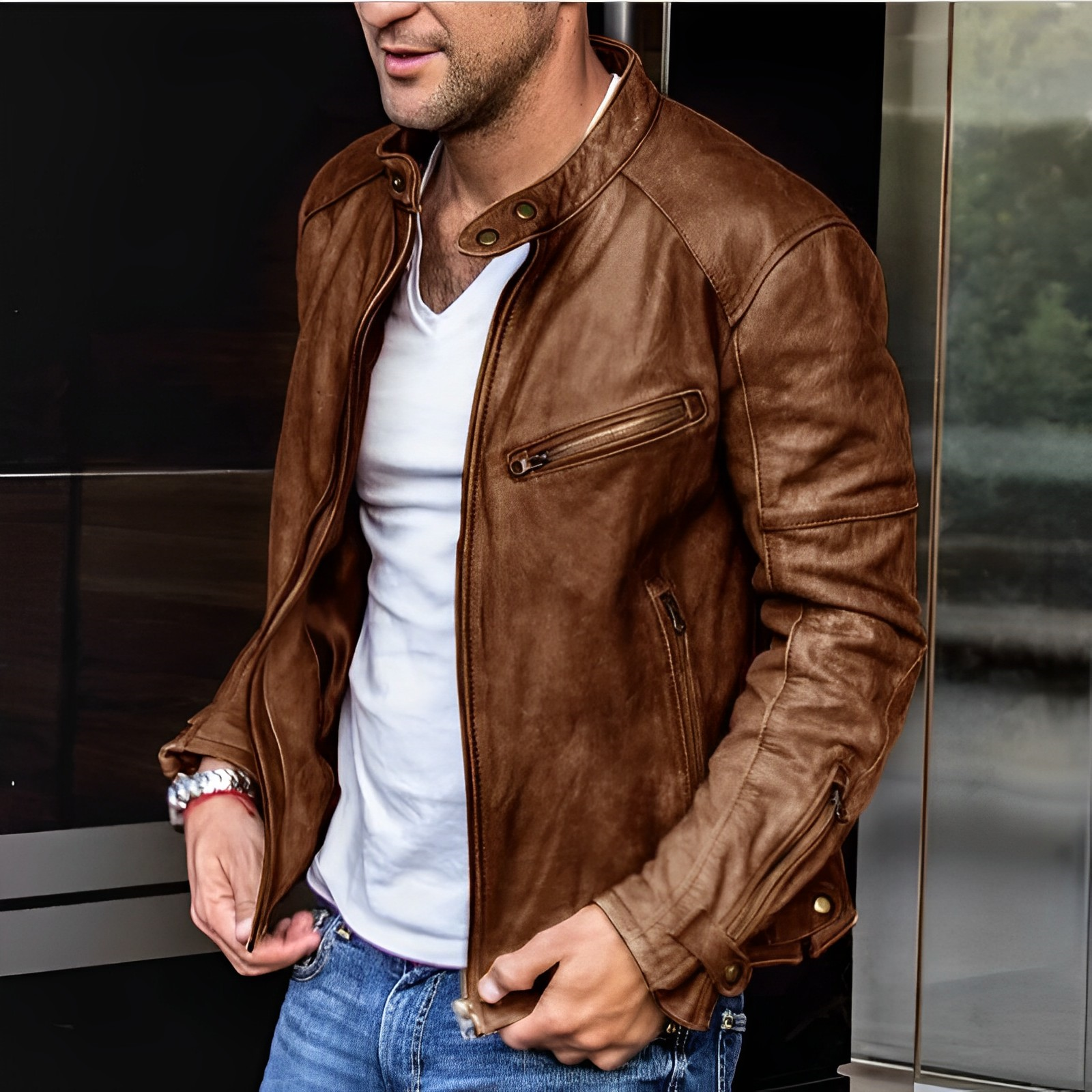 Giacca in pelle marrone da uomo, stile casual, con zip e tasche, abbinata a jeans e maglietta bianca. Moda maschile autunnale.