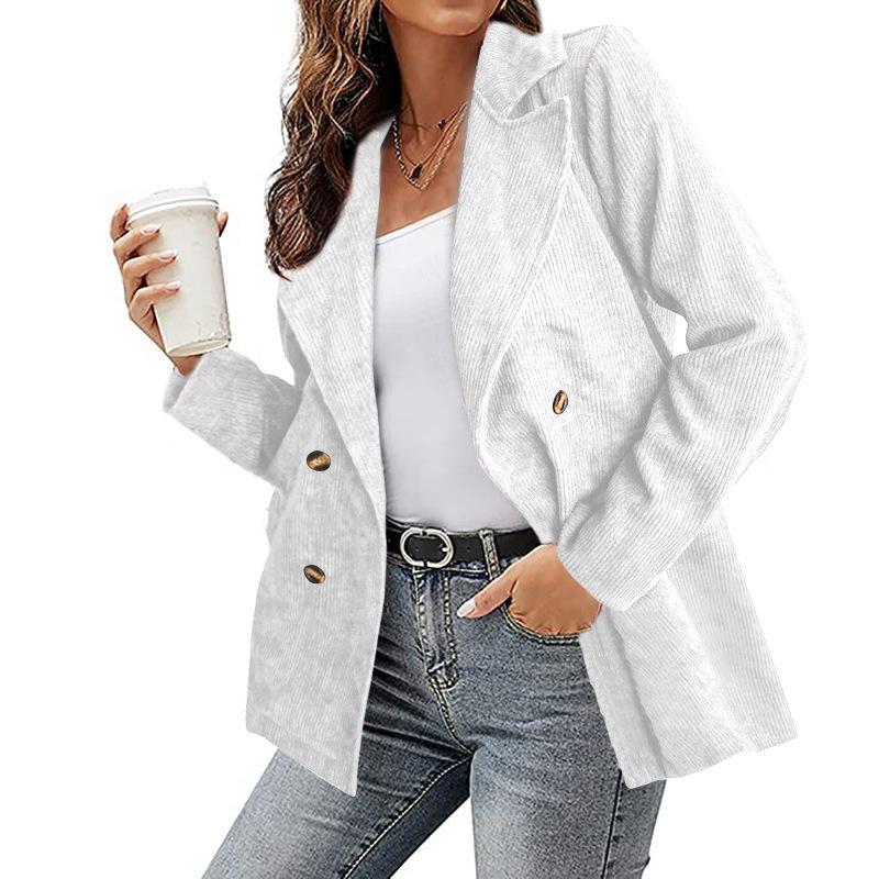 Donna con blazer bianco a doppio petto, jeans e cintura nera, tiene una bevanda. Moda casual elegante, abbigliamento femminile autunnale.