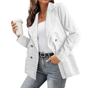 Donna con blazer bianco a doppio petto, jeans e cintura nera, tiene una bevanda. Moda casual elegante, abbigliamento femminile autunnale.