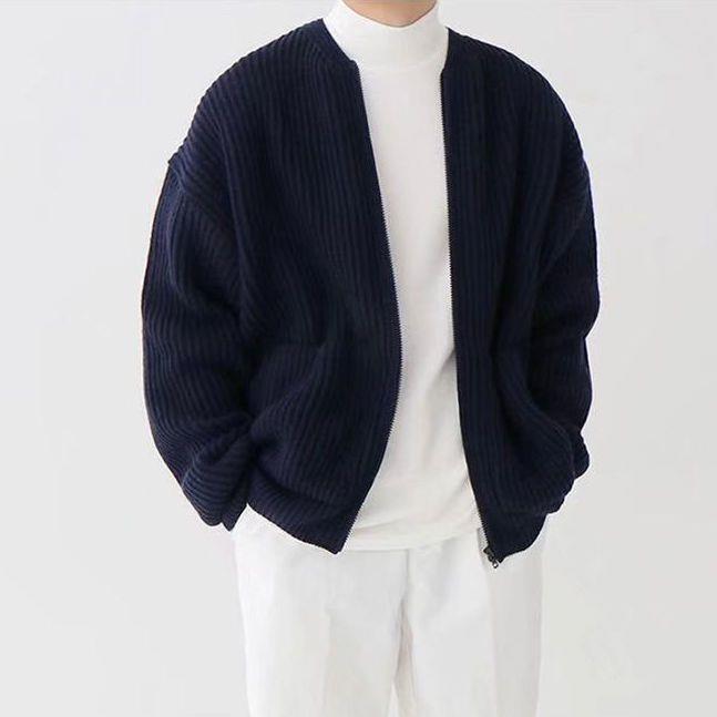 Giacca cardigan blu scuro a coste, indossata su maglione bianco e pantaloni bianchi. Moda uomo casual, abbigliamento autunnale elegante.
