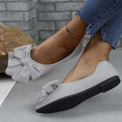 Scarpe ballerine grigie con fiocco, indossate con jeans. Calzature eleganti e comode per donna, ideali per moda casual e quotidiana.