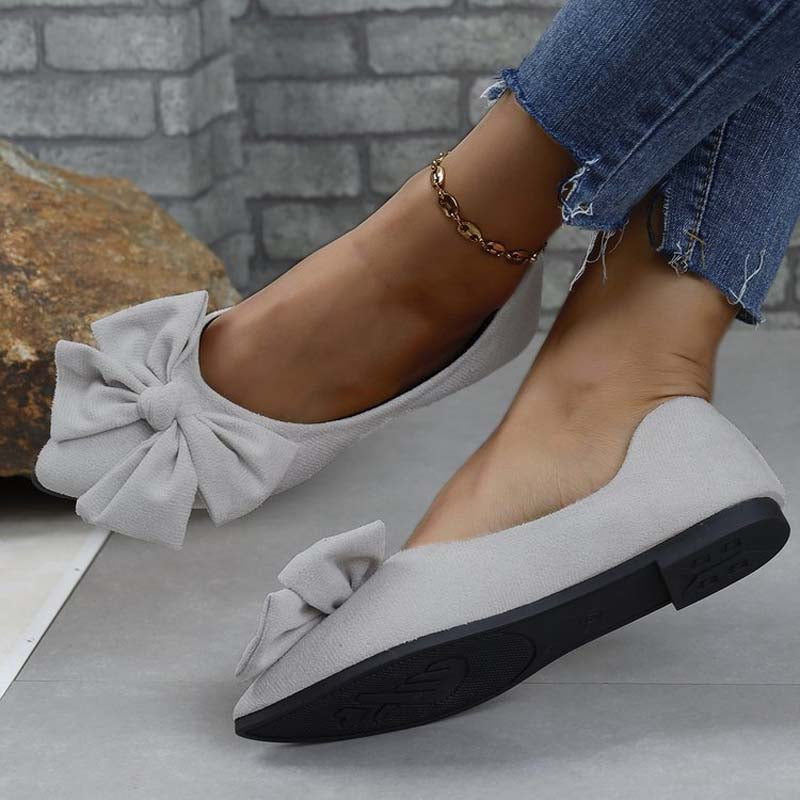 Scarpe ballerine grigie con fiocco, indossate con jeans. Calzature eleganti e comode per donna, ideali per moda casual e quotidiana.