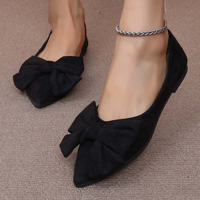 Scarpe ballerine nere da donna con fiocco, indossate su tappeto beige. Eleganti e comode, ideali per moda casual e formale.