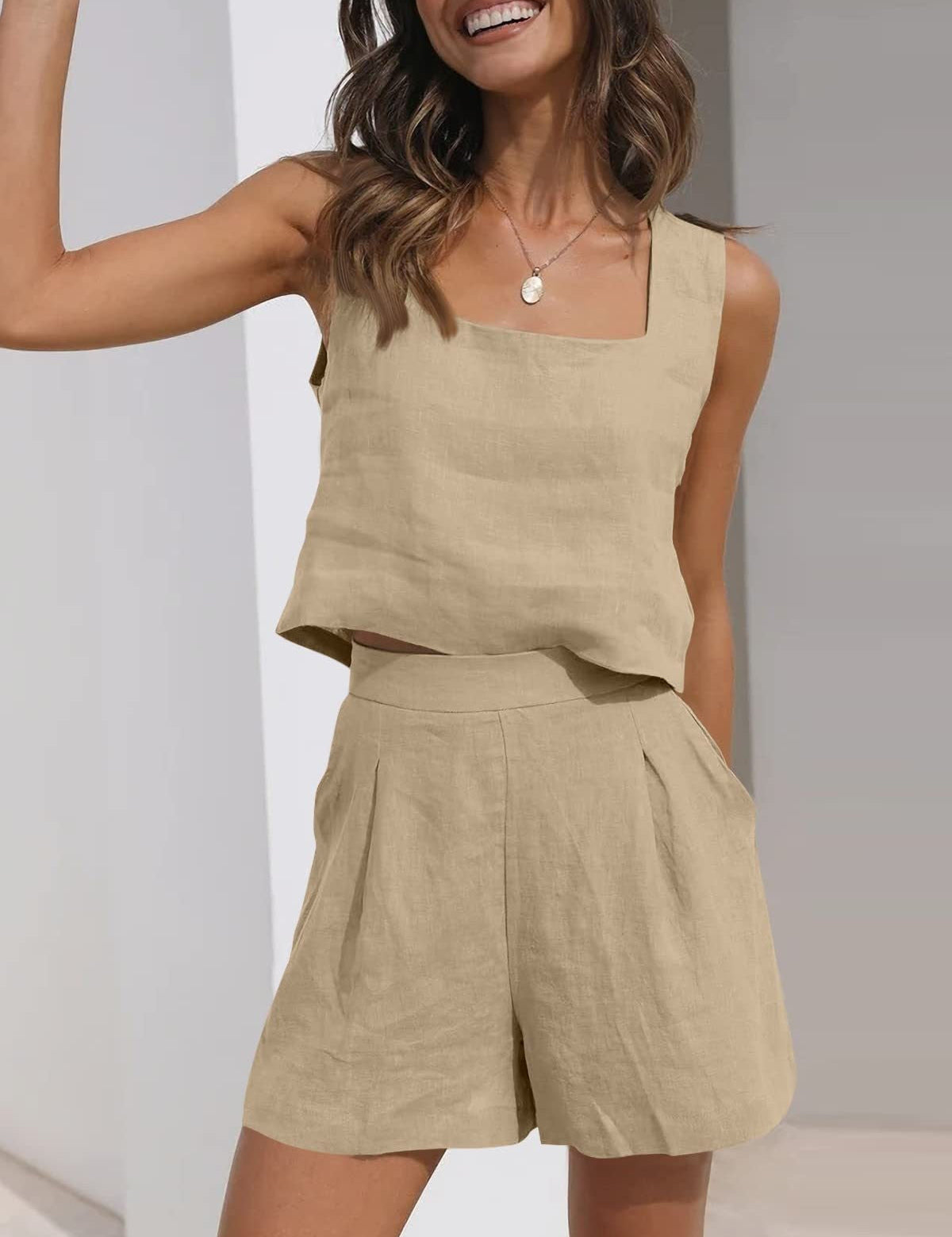 Donna che indossa un completo estivo beige in lino, composto da top senza maniche e pantaloncini a vita alta. Moda casual, abbigliamento leggero.