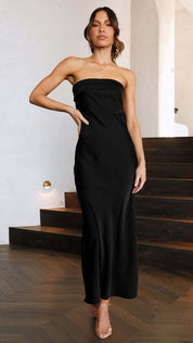Abito lungo nero elegante senza spalline, indossato da una donna su scala interna. Perfetto per eventi serali e cerimonie.