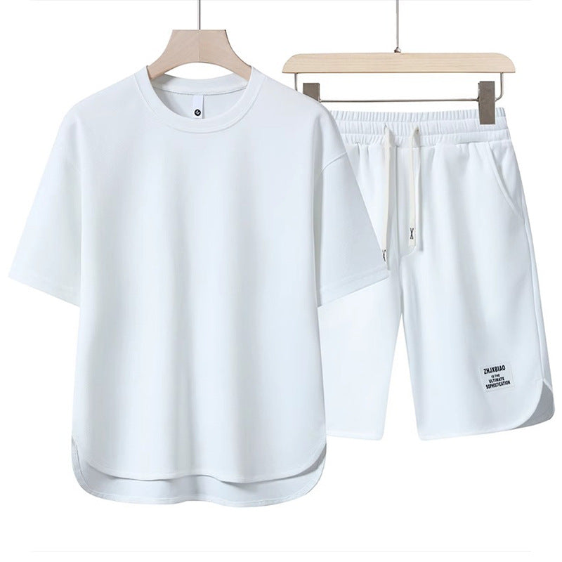 Set abbigliamento sportivo bianco, maglietta e pantaloncini in cotone, design minimalista, ideale per palestra e attività all'aperto.