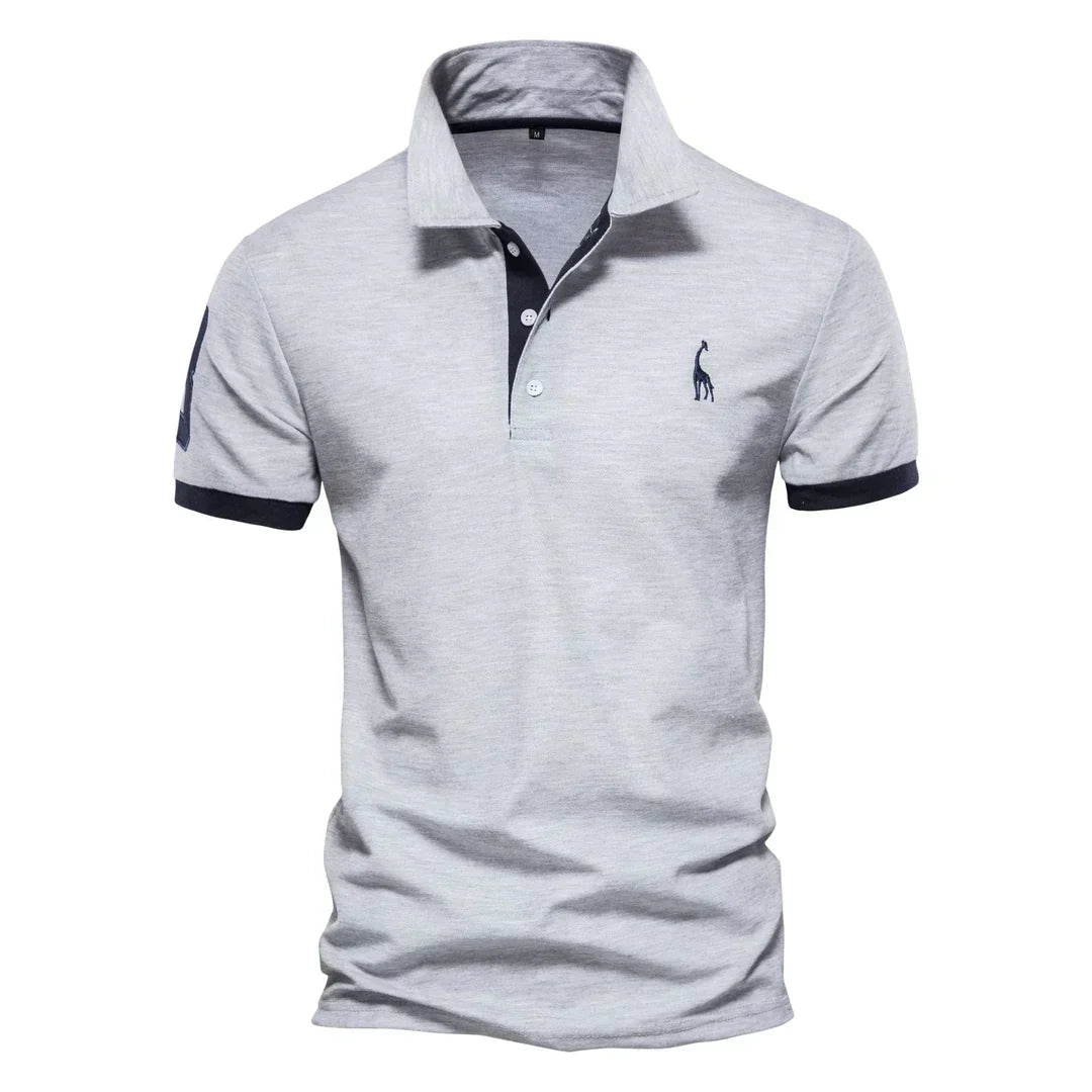 Polo uomo grigia, maniche corte, colletto classico, logo ricamato, dettagli blu scuro. Elegante e casual, ideale per moda maschile estiva.