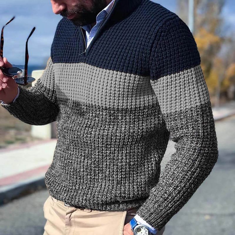 Maglione uomo a righe blu e grigie, lavorato a maglia, con zip, indossato con pantaloni beige. Stile casual autunnale.