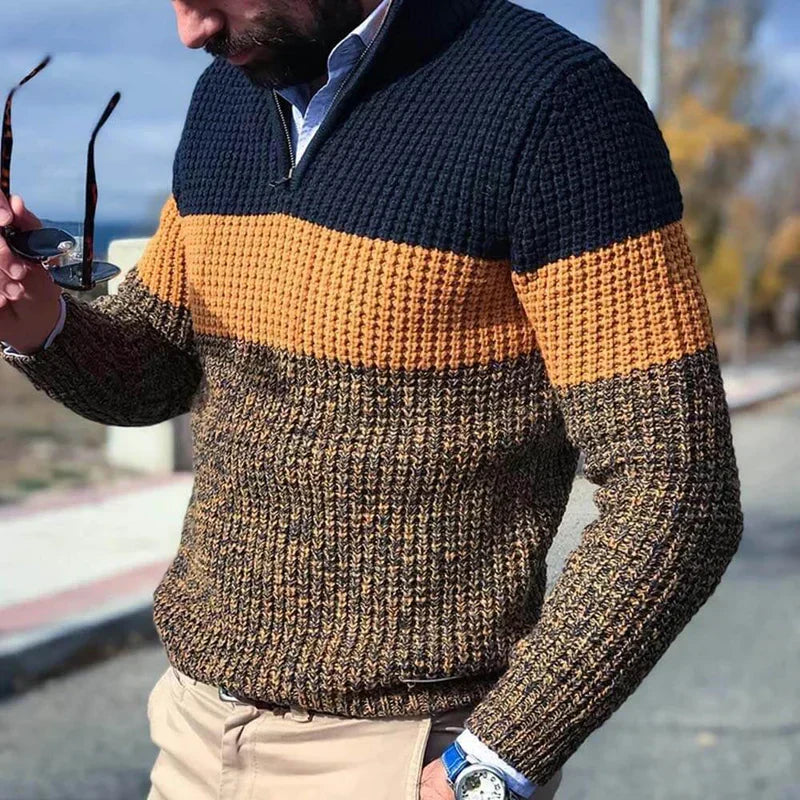 Maglione uomo a righe blu, arancione e marrone, lavorato a maglia, con zip, indossato all'aperto. Stile casual autunnale, moda maschile.