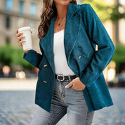 Donna con giacca blu a coste, top bianco e jeans, tiene una tazza da caffè. Moda urbana, abbigliamento casual chic, stile autunnale.