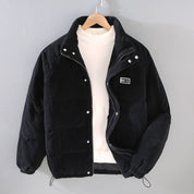 Giacca invernale nera in velluto a coste, con bottoni e cerniera, su gruccia. Design casual, ideale per moda uomo autunno-inverno.