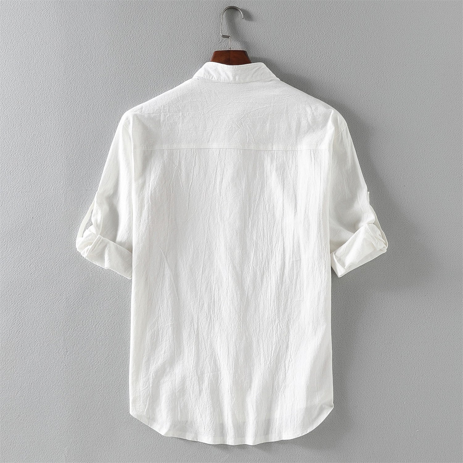 Camicia bianca da uomo in cotone, maniche lunghe arrotolate, appesa su gruccia. Design classico, ideale per look casual ed eleganti.