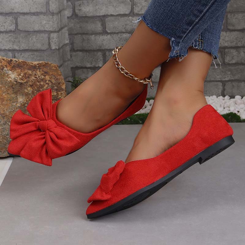 Scarpe ballerine rosse con fiocco, indossate con jeans strappati. Calzature eleganti da donna, moda casual, tendenza autunno.