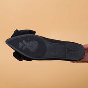 Suola di scarpa nera con design a cuore e mano, sfondo beige. Scarpe moda donna, calzature eleganti, dettagli unici.