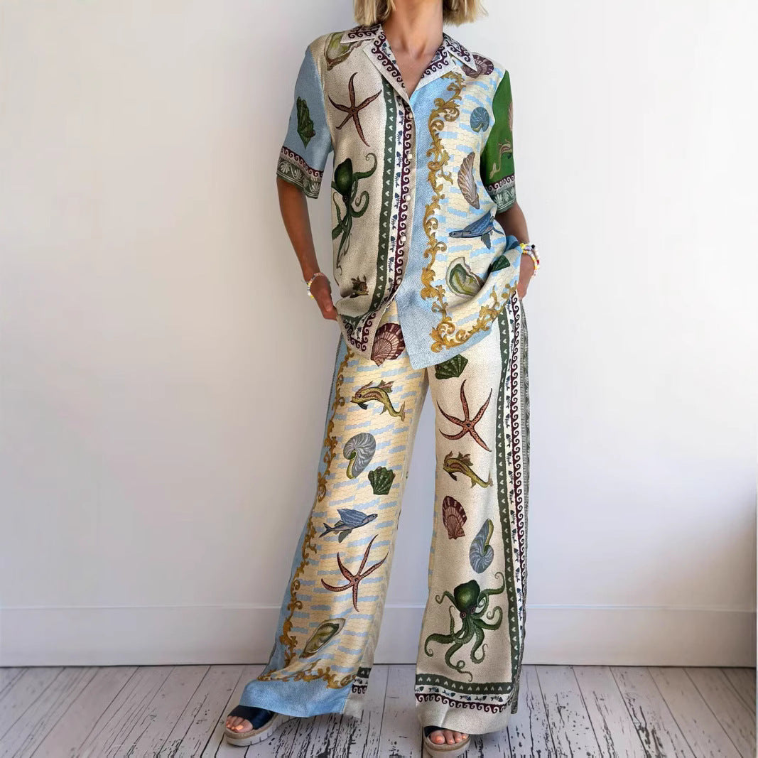 Donna in completo estivo con camicia e pantaloni stampati con motivi marini, come polpi e conchiglie, su sfondo bianco. Moda casual elegante.