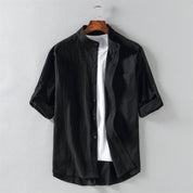Camicia nera da uomo in cotone, maniche lunghe arrotolate, colletto alla coreana, abbinata a t-shirt bianca. Elegante e casual.