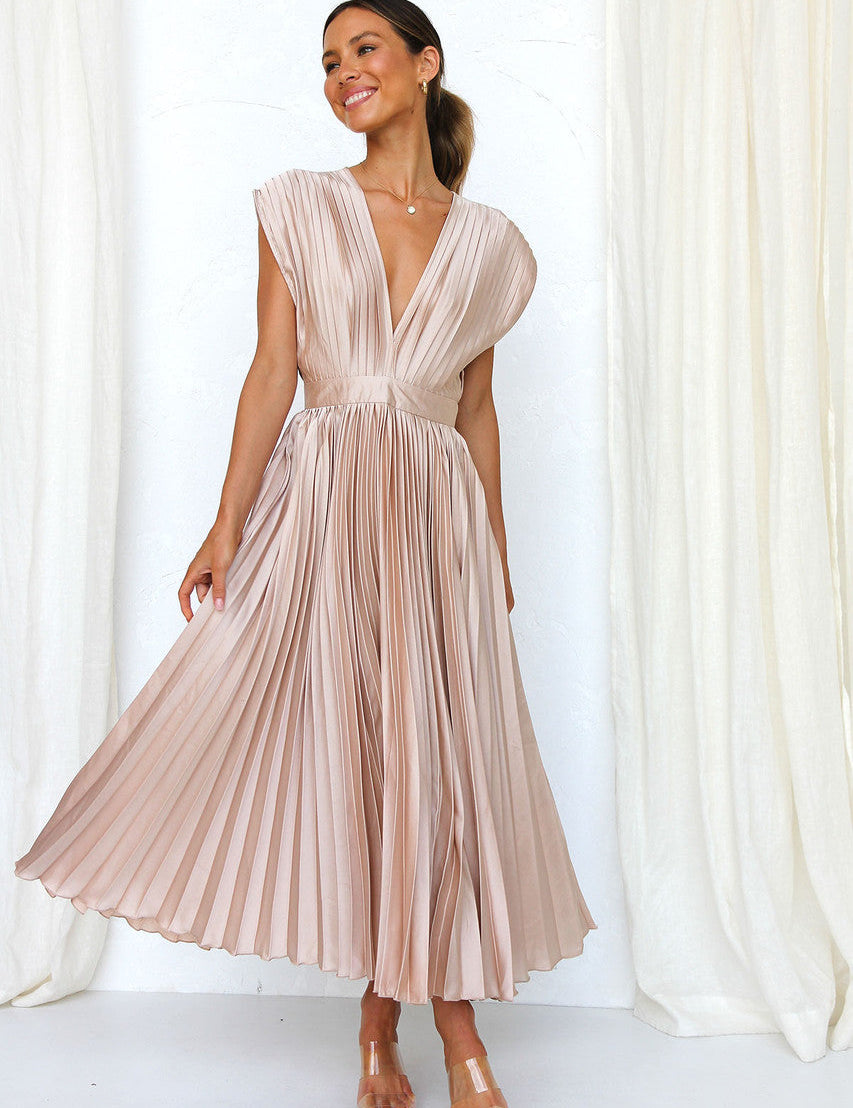 Abito lungo plissettato color champagne, scollatura a V profonda, indossato da donna sorridente. Elegante moda femminile, abbigliamento estivo.