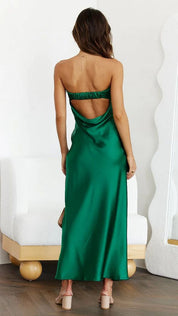 Abito lungo verde smeraldo in raso, schiena scoperta, indossato da donna. Elegante e moderno, perfetto per eventi serali e cerimonie.