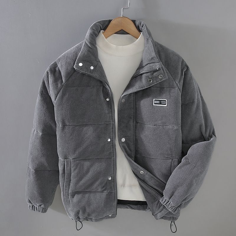 Giacca invernale grigia in velluto a coste, con colletto alto e chiusura a bottoni, appesa su gruccia. Design casual, ideale per moda uomo.