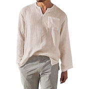 Camicia uomo in lino bianco, maniche lunghe, scollo a V, taschino frontale, abbinata a pantaloni a righe. Stile casual estivo elegante.