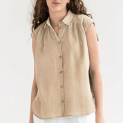 Blusa senza maniche beige in lino, con colletto classico e bottoni frontali. Moda donna estiva, abbigliamento casual elegante.