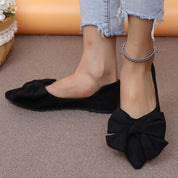 Scarpe ballerine nere con fiocco, indossate con jeans strappati. Eleganti e alla moda, ideali per look casual e chic. Accessorio cavigliera argento.