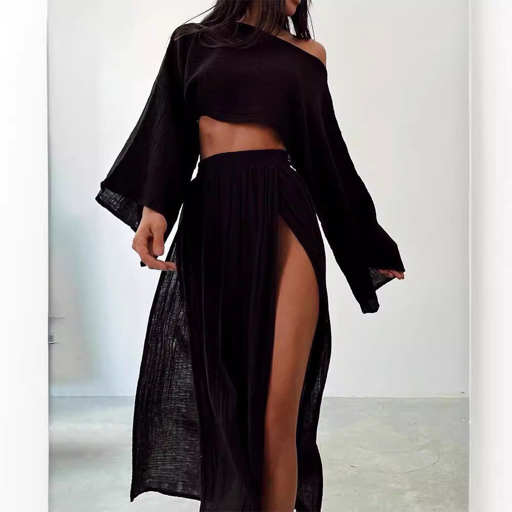 Abito nero elegante con spacco alto, maniche lunghe e scollo asimmetrico. Moda donna, abbigliamento trendy per serate e occasioni speciali.