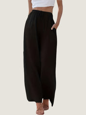 Pantaloni neri larghi da donna, vita alta con coulisse, tasche laterali, abbinati a top bianco corto e sandali. Moda casual estiva.