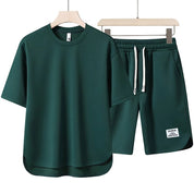 Set coordinato uomo verde scuro, composto da t-shirt a maniche corte e pantaloncini con coulisse. Abbigliamento casual estivo, moda uomo.