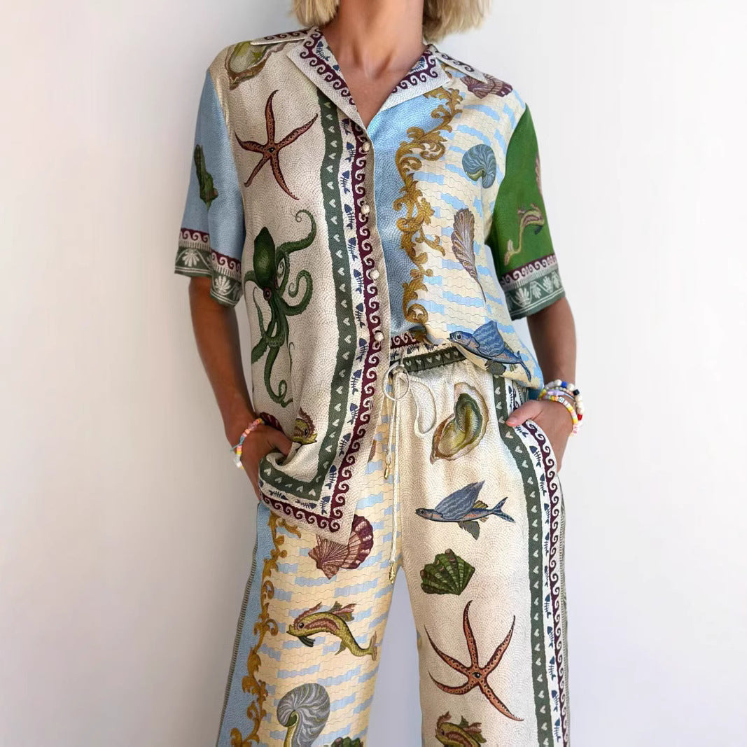 Completo estivo donna con stampa marina, polpo e conchiglie, camicia e pantaloni coordinati, moda casual, sfondo bianco.