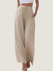 Pantaloni palazzo beige da donna, vita alta con coulisse, tessuto leggero, tasche laterali, abbinati a top bianco. Eleganti e comodi per l'estate.