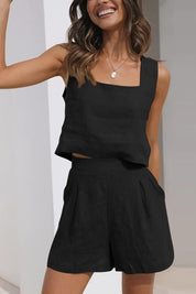 Donna sorridente indossa completo estivo nero, top senza maniche e pantaloncini a vita alta. Moda casual elegante, abbigliamento estivo donna.