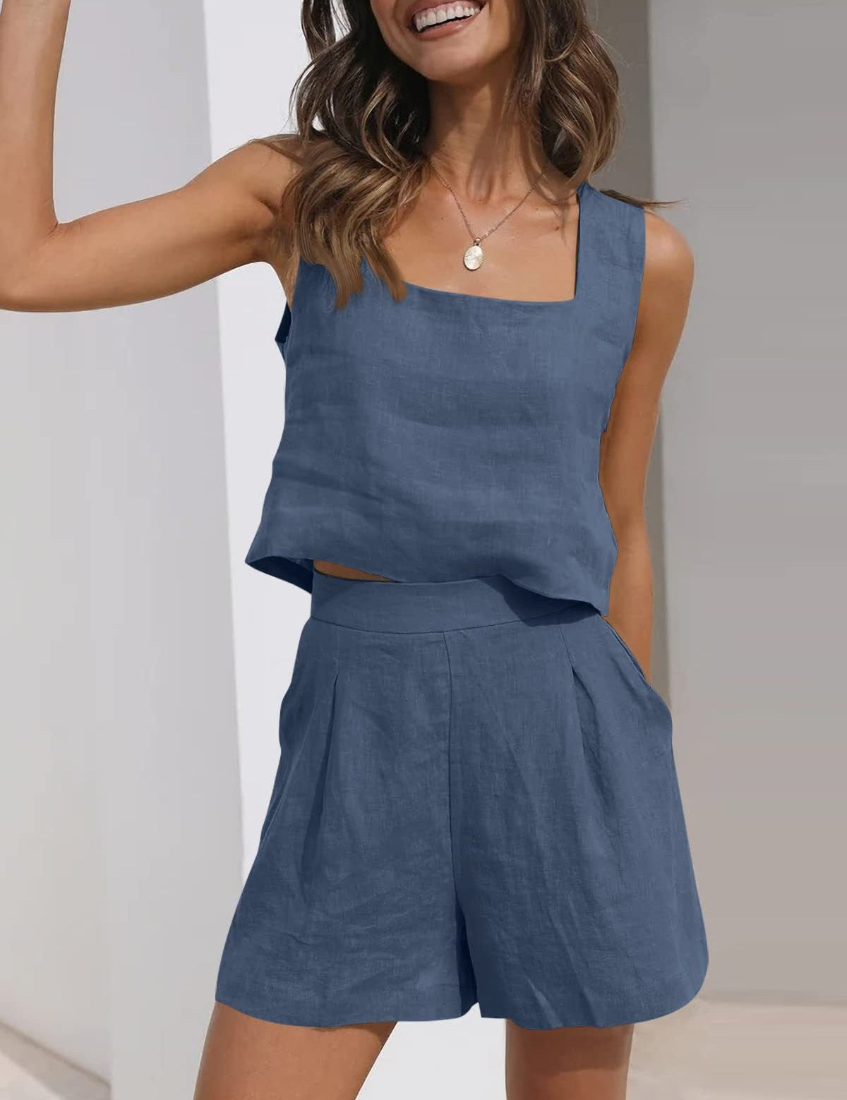 Donna sorridente in completo estivo blu, top senza maniche e pantaloncini a vita alta. Moda casual, abbigliamento leggero, look estivo elegante.