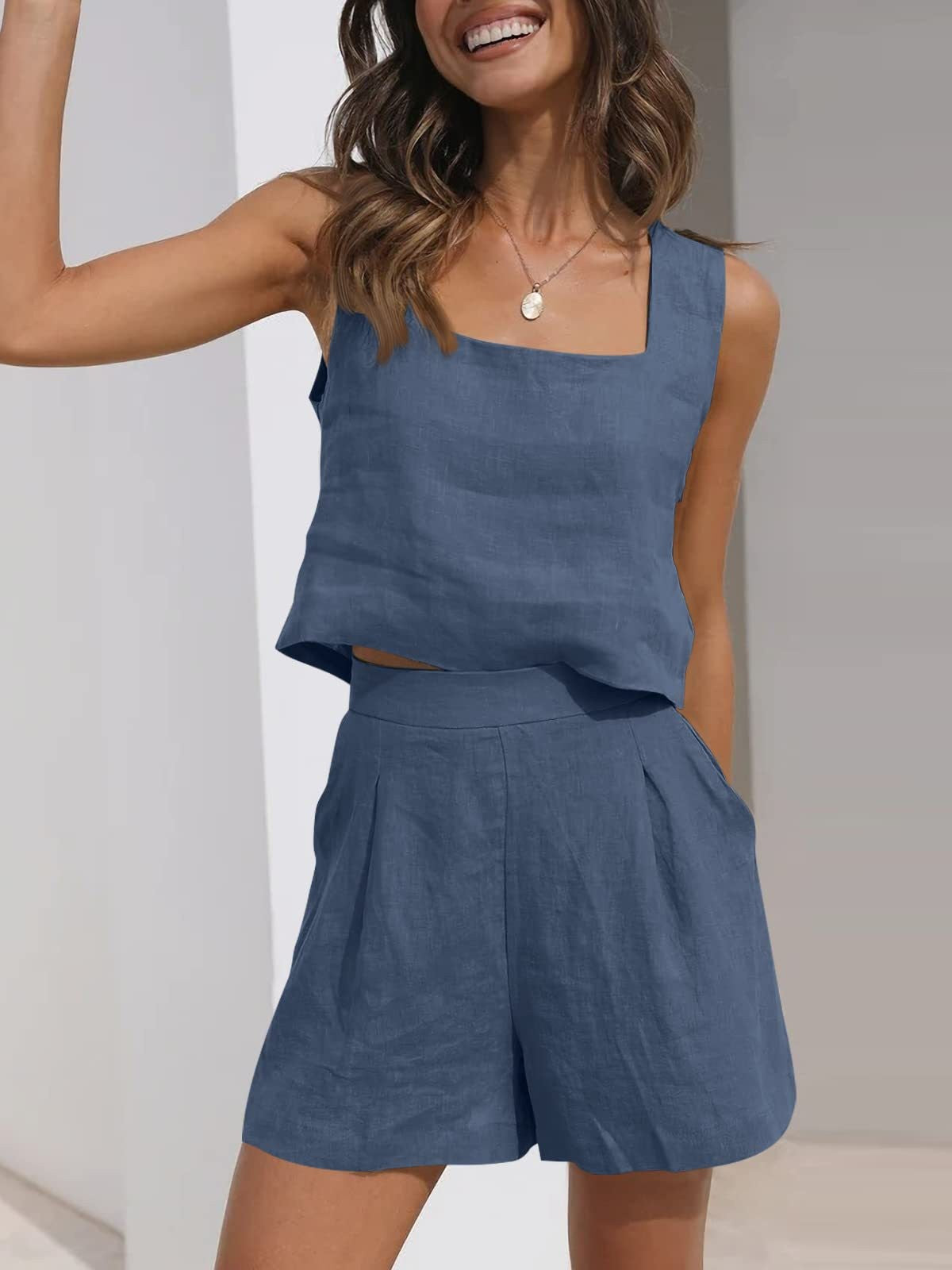 Donna sorridente in completo estivo blu, top senza maniche e pantaloncini a vita alta. Moda casual, abbigliamento leggero, look estivo elegante.