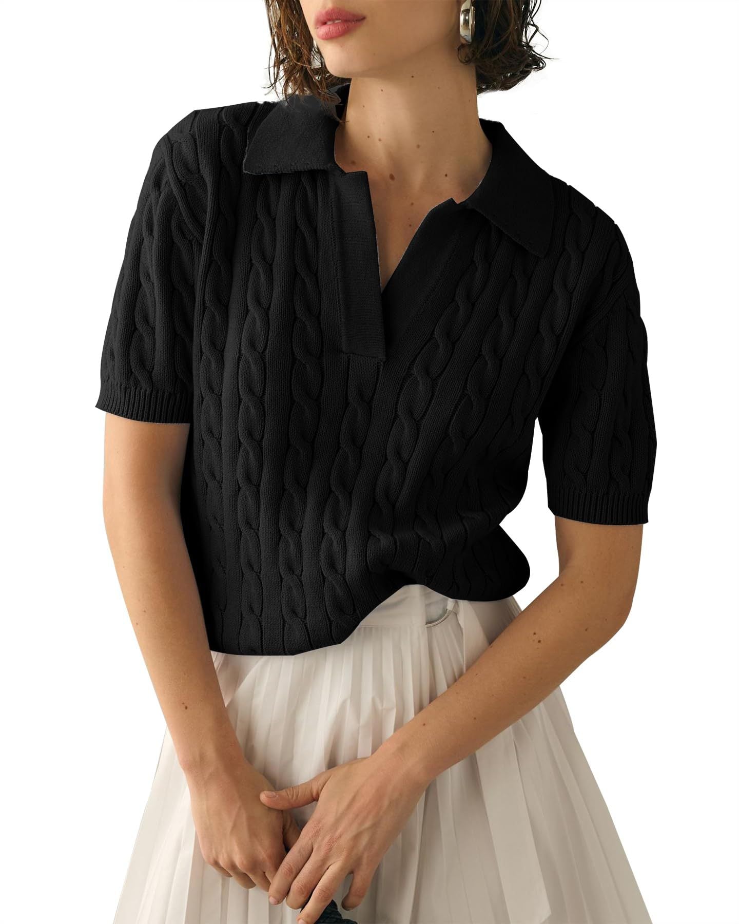 Donna indossa maglione nero a trecce con colletto e maniche corte, abbinato a gonna bianca plissettata. Moda elegante, abbigliamento casual chic.