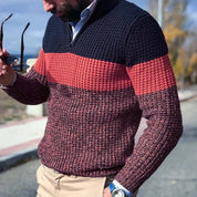 Maglione uomo a righe blu e rosse, lavorato a maglia, indossato con pantaloni beige. Stile casual autunnale, moda maschile elegante.