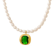 Collana di perle bianche con ciondolo in oro e pietra verde smeraldo. Gioiello elegante, accessorio di lusso, moda femminile.
