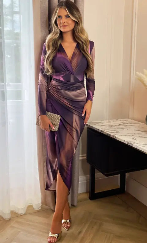 Abito elegante donna viola con drappeggio, maniche lunghe, scollo a V, abbinato a pochette argento e sandali. Moda femminile, abbigliamento serale.