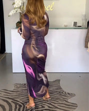 Abito lungo viola con stampa astratta, indossato da una donna in un negozio di moda. Design elegante, perfetto per eventi serali.