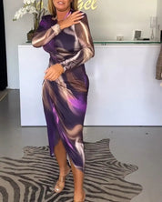 Abito lungo elegante viola e marrone con motivo astratto, indossato da una donna in un negozio di moda. Scarpe trasparenti, tappeto zebrato.