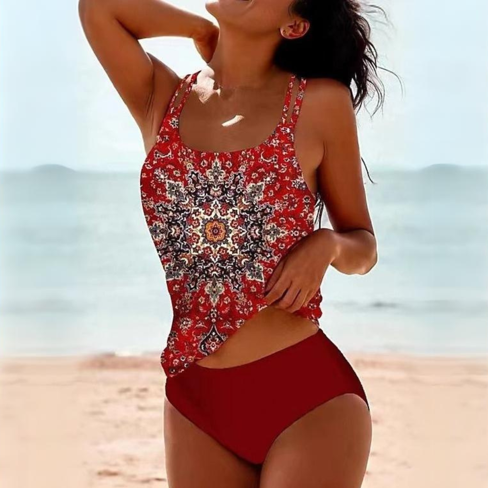 Donna in costume da bagno rosso con stampa mandala, spiaggia sullo sfondo. Moda mare, abbigliamento estivo, costumi da bagno eleganti.