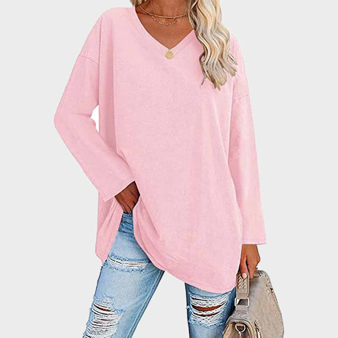 Donna con maglia oversize rosa, jeans strappati, borsa beige. Moda casual femminile, abbigliamento trendy, look autunnale.