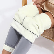 Pantaloni termici in pile bianco, indossati sopra leggings grigi. Ideali per l'inverno, offrono calore e comfort. Perfetti per attività all'aperto.