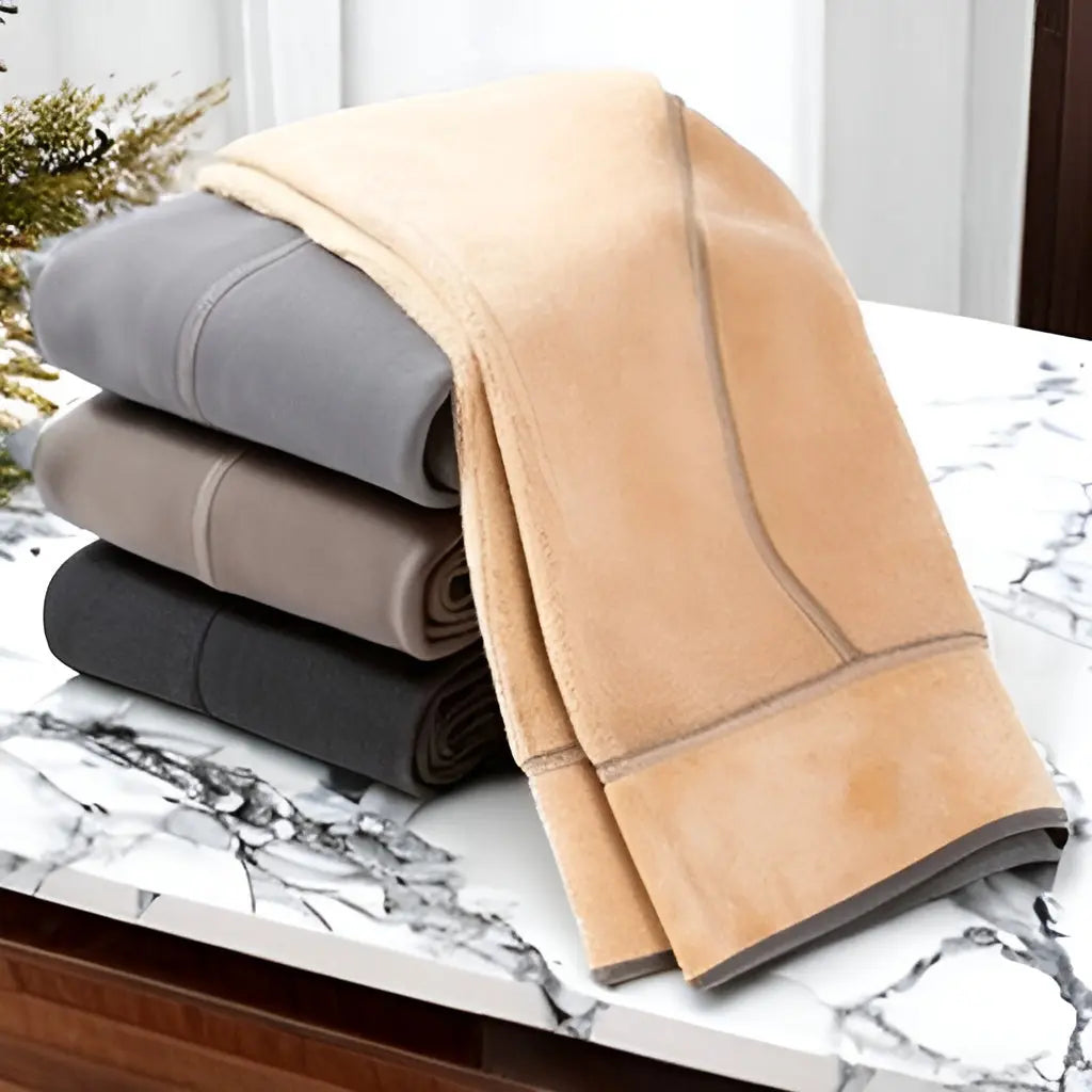 Coperte in pile morbido, colori beige, grigio e nero, su tavolo marmo. Ideali per soggiorno, camera da letto. Accessori casa caldi e accoglienti.